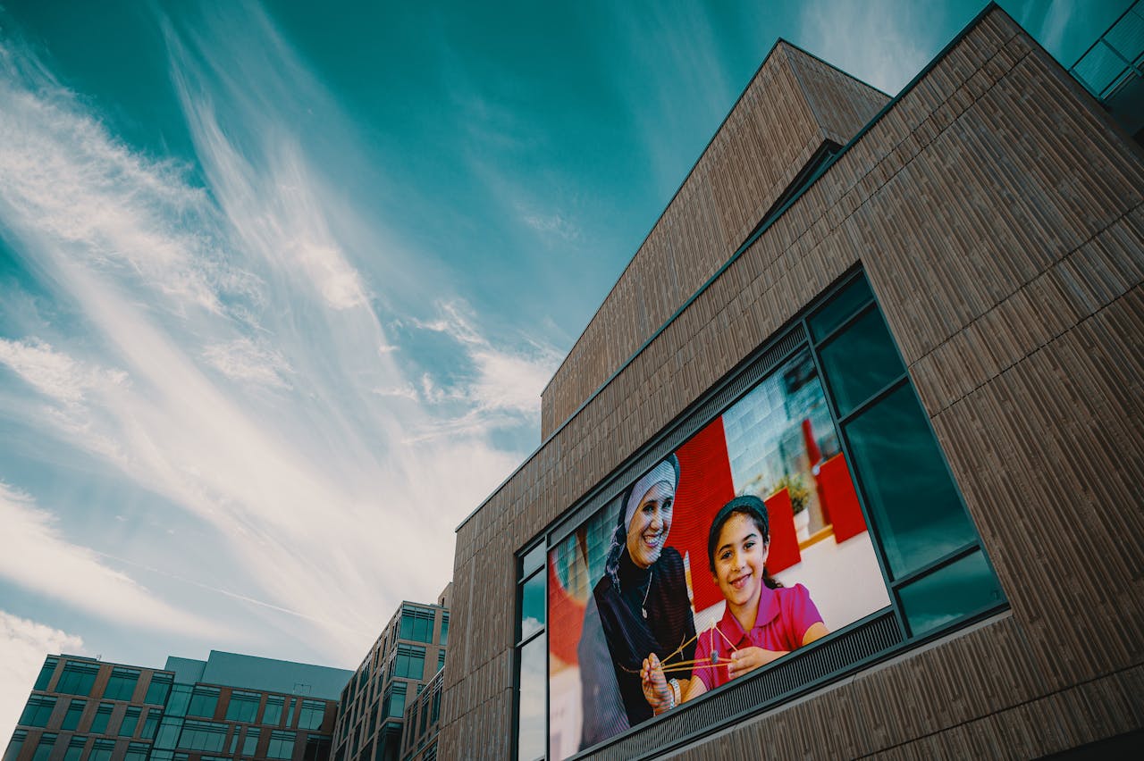 Modern building facade showcasing a large digital screen displaying a vibrant image against a blue sky.